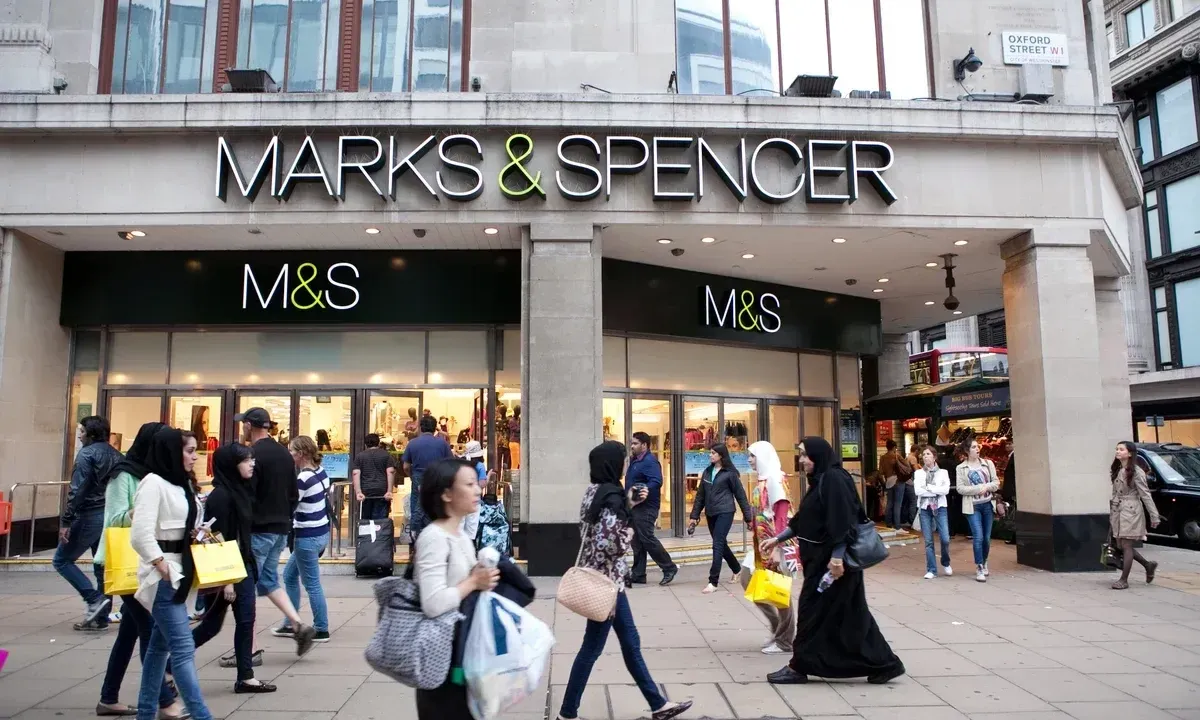 External shot of a Marks & Spencers with a people walking by in front of it