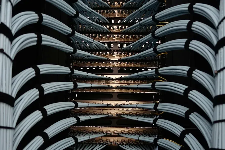 Ethernet cables going into the back of a rack of network switches