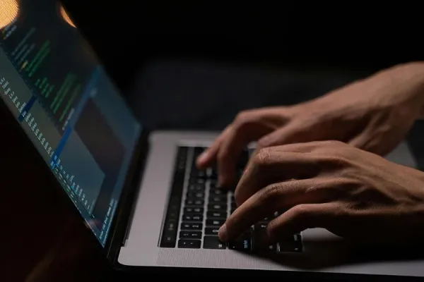 Hands typing on an open laptop