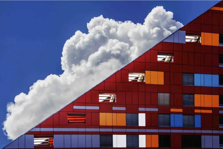 Triangular red building with white cloud behind it