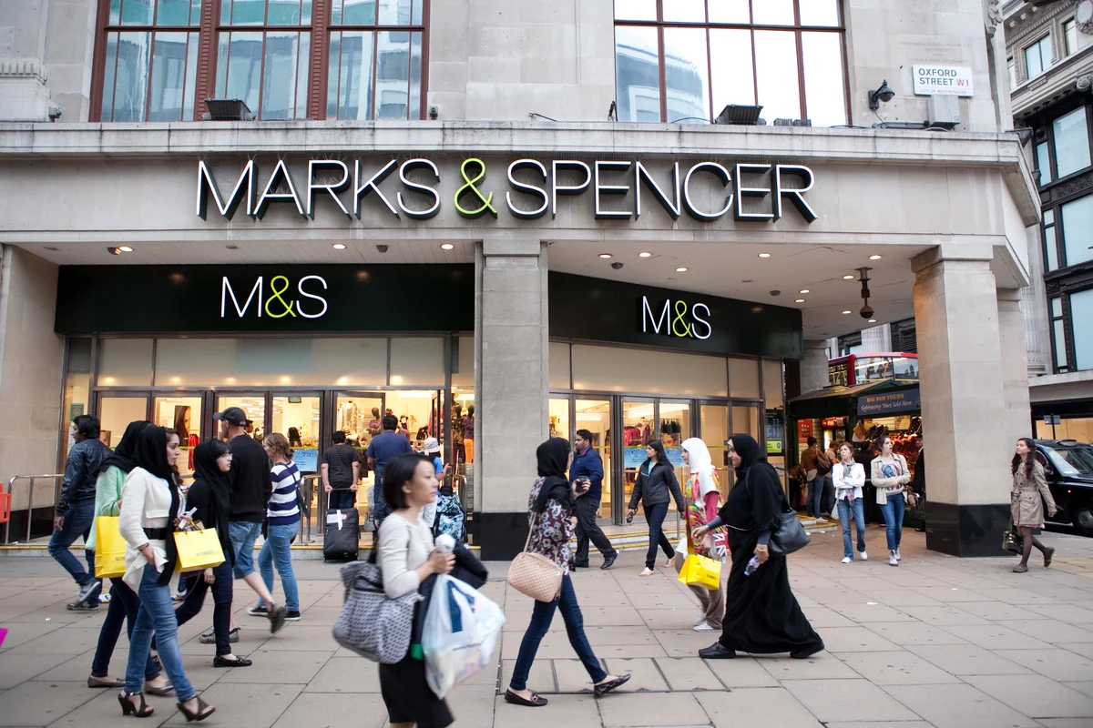 External shot of a Marks & Spencers with a people walking by in front of it