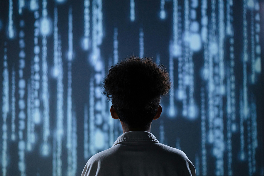 Photo from behind of a young person watching a projection of cascading numbers