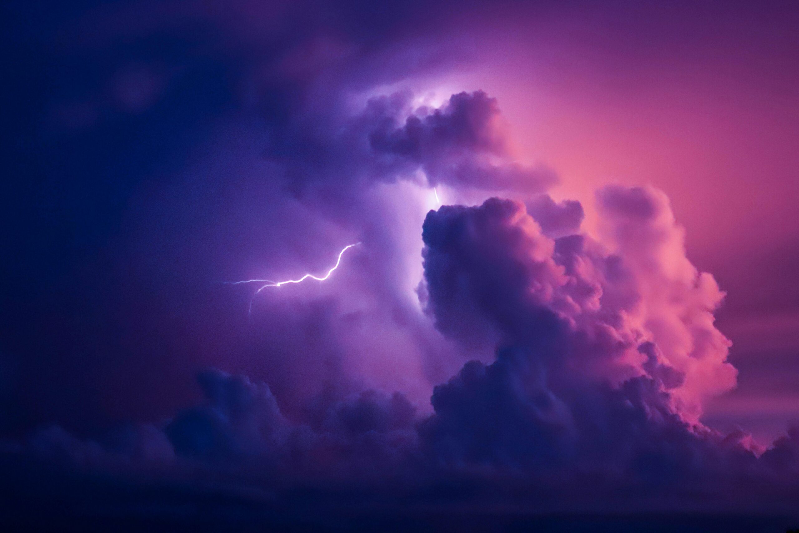 Lightning arcing through pink and purple clouds